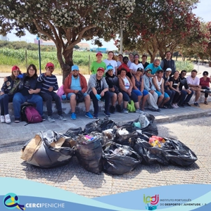 Grupo de pessoas apoiadas pela Cercipeniche e colaboradores em atividade de Plogging junto a praia recolhendo lixo. Logo, e elemento gráfico.