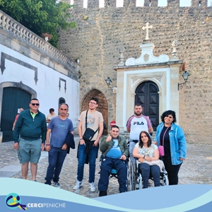 Grupo de pessoas apoiadas da Cercipeniche, Junto a entrada do Castelo de Óbidos. No festival de Teatro em Óbidos. Logotipos e elemento gráfico.