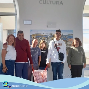Grupo de pessoas apioadas pela Cercipeniche na Biblioteca Municipal de Peniche recebendo um cabaz com géneros alimentícios.