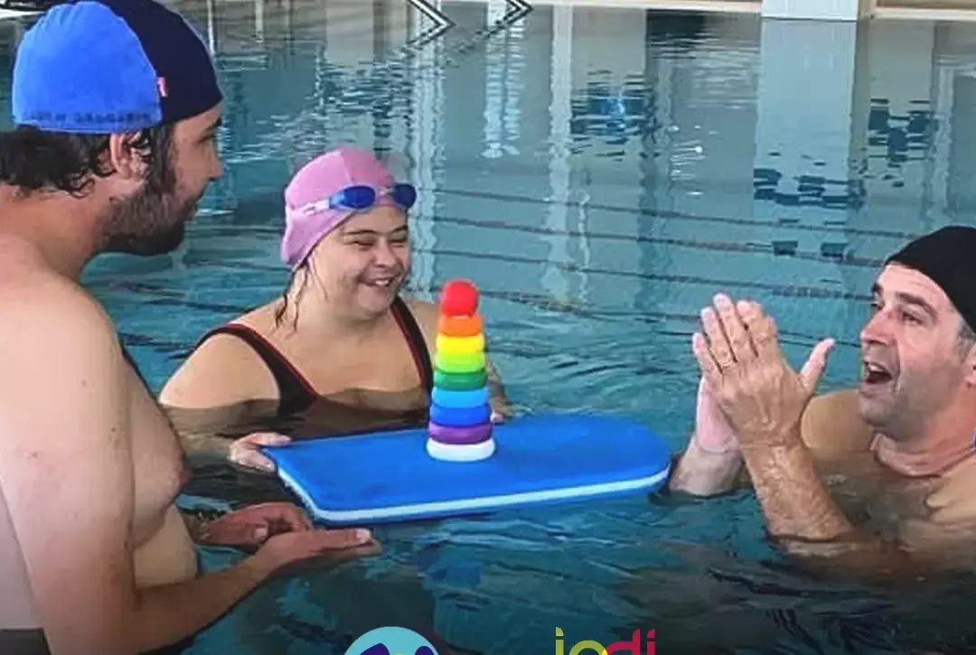 Pessoas apoiadas pela Cercipeniche em atividade aquática, uma das modalidades que o projeto Aqua + promove. Logo Cercipeniche