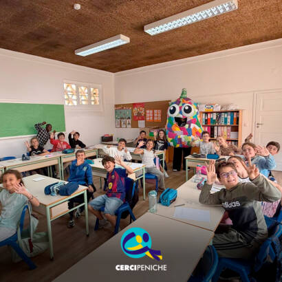 Foto com crianças dentro da sala de aulas, ao fundo está a mascote do Pirilampo Mágico. Logo da Cercipeniche.