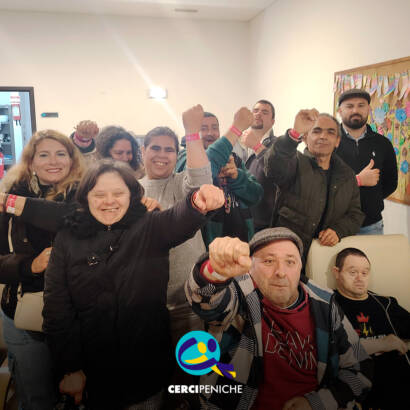 Grupo de pessoas apoiadas pela Cercipeniche animadas à chegada ao Festival Rock in Rei. Logo da Cercipeniche.