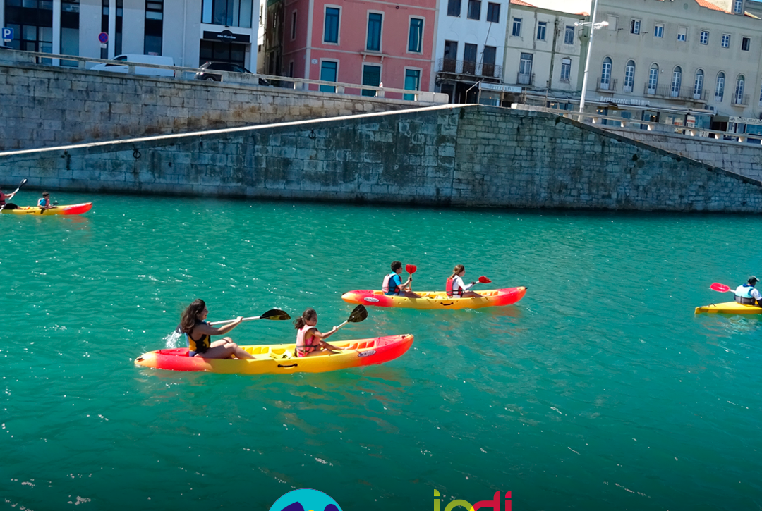 Pessoas apoiadas e crianças durante uma atividade de canoagem. Logo da Cercipeniche.