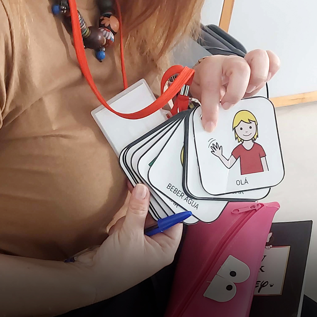 Foto com uma senhora a mostrar cartões com símbolos para apoio à comunicação.