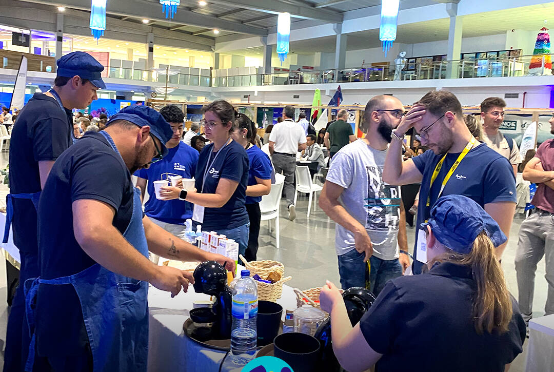 Pessoas apoiadas pela Cercipeniche a servir os visitantes na Bienal do Mar. Logo da Cercipeniche.
