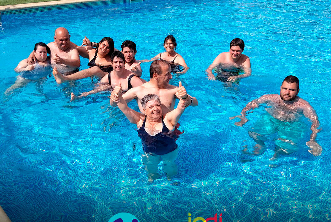 Pessoas apoiadas a sorrir para a fotografia dentro da piscina. Logo da Cercipeniche e do IPDJ.