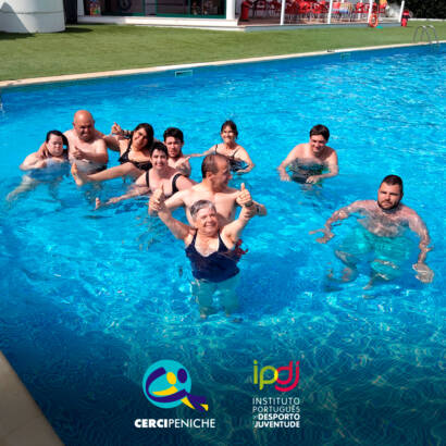 Pessoas apoiadas a sorrir para a fotografia dentro da piscina. Logo da Cercipeniche e do IPDJ.
