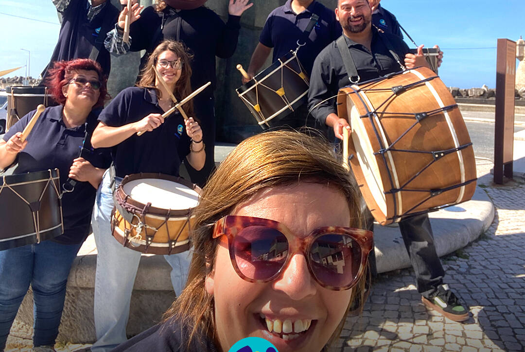 Grupo de Bombos da Cercipeniche pousam para a foto junto à estátua do Pescador, ao pé da ribeira. Logo da Cercipeniche.