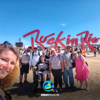 Pessoas apoiadas pela Cercipeniche pousam para a foto junto à entrada do Rock in Rio Lisboa. Ao fundo vê-se o logótipo do "Rock in Rio". Logótipo da Cercipeniche.