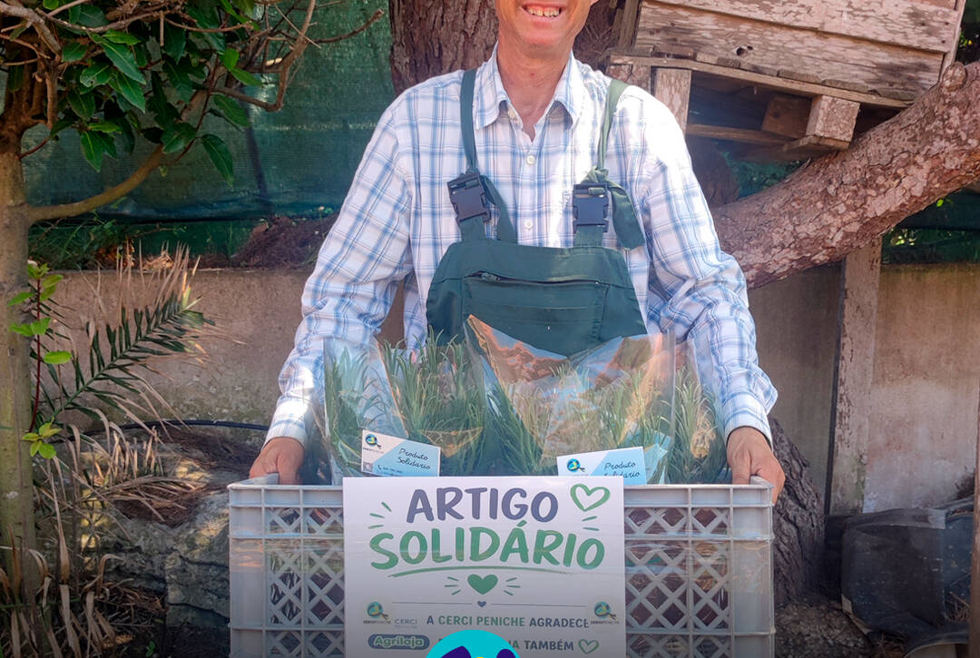 Pessoa apoiada pela Cercipeniche a mostrar as caixas com as alfazemas para entrega na Agriloja de Peniche. Logo da Cercipeniche.