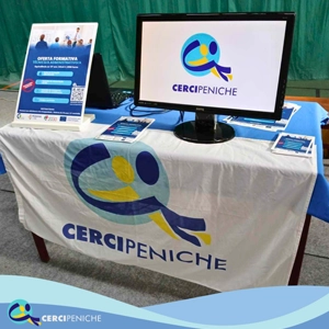 Foto mesa com bandeira e flyer da Cercipeniche em atividade de divulgação certame “Sun7: 9º Ano e Agora