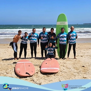 Grupo de pessoas apoiadas da Cercipeniche, junto com instrutores de surf em aula de aptidão na praia. Logotipos e elemento gráfico.