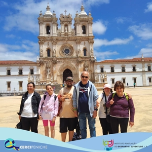 Grupo de pessoas apoiadas pela Cercipeniche em frente ao Armazém das Artes de Alcobaça. Logo, e elemento gráfico.