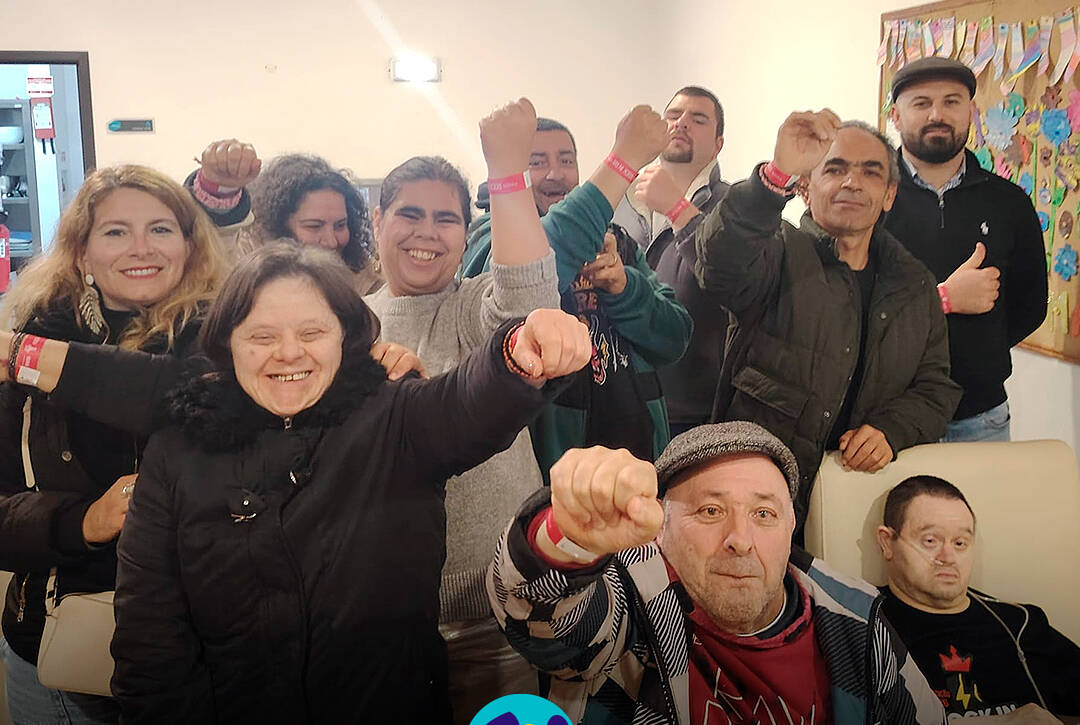 Grupo de pessoas apoiadas pela Cercipeniche animadas à chegada ao Festival Rock in Rei. Logo da Cercipeniche.