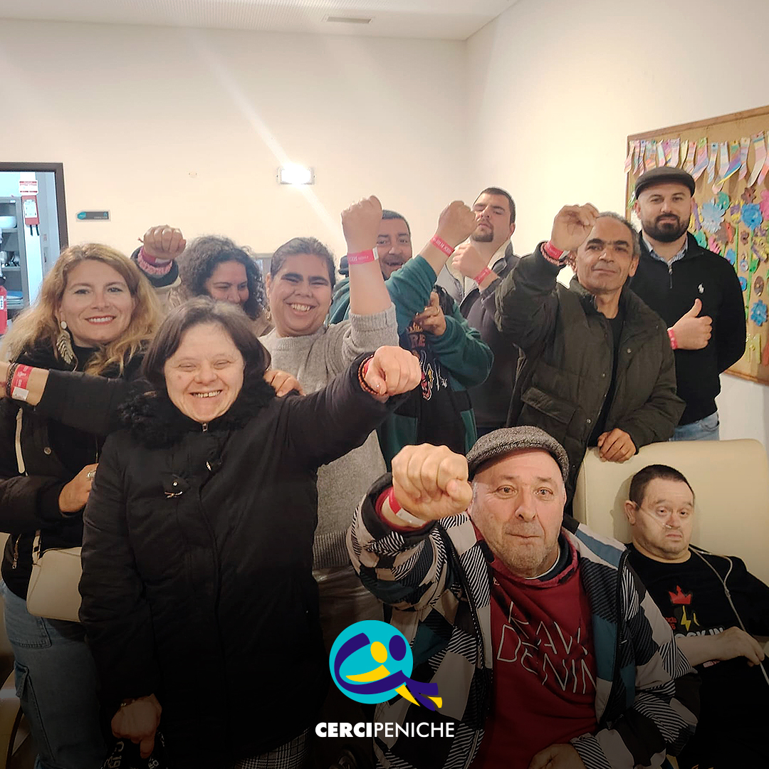 Grupo de pessoas apoiadas pela Cercipeniche animadas à chegada ao Festival Rock in Rei. Logo da Cercipeniche.