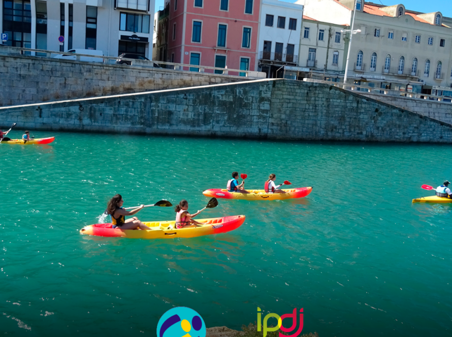 Pessoas apoiadas e crianças durante uma atividade de canoagem. Logo da Cercipeniche.