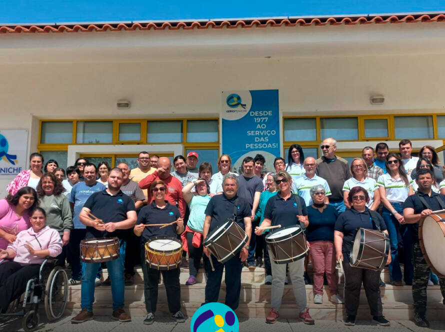 Pessoas apoiadas e colaboradores da Cercipeniche, juntamente com as representantes da associação Peniche a Correr, posam em grupo com os bombos e a tarolas oferecidos. Logo da Cercipeniche.