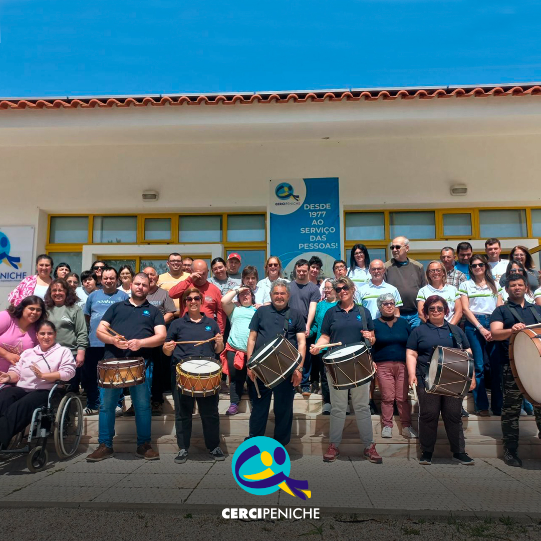 Pessoas apoiadas e colaboradores da Cercipeniche, juntamente com as representantes da associação Peniche a Correr, posam em grupo com os bombos e a tarolas oferecidos. Logo da Cercipeniche.