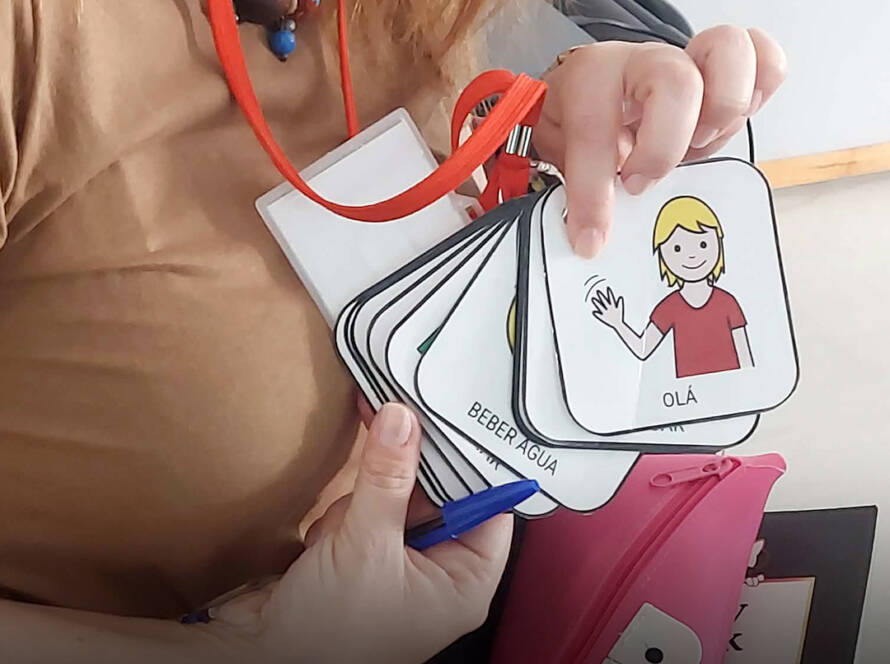 Foto com uma senhora a mostrar cartões com símbolos para apoio à comunicação.
