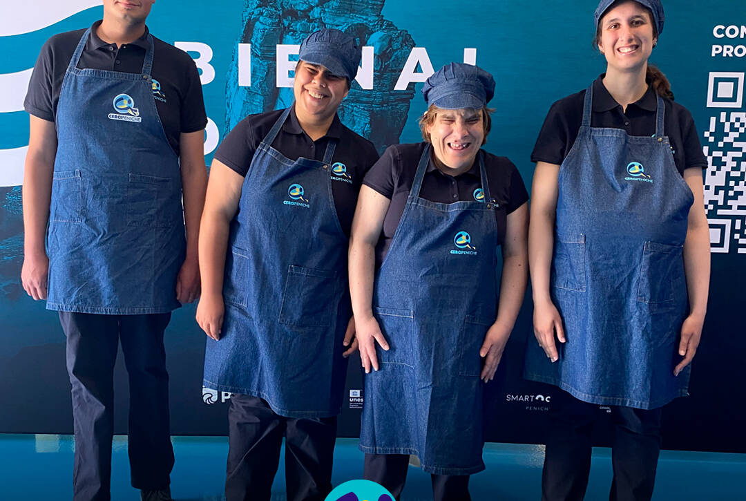 Grupo de participantes pousam para a foto, felizes, antes do início da atividade na Bienal do Mar. Logo da Cercipeniche.