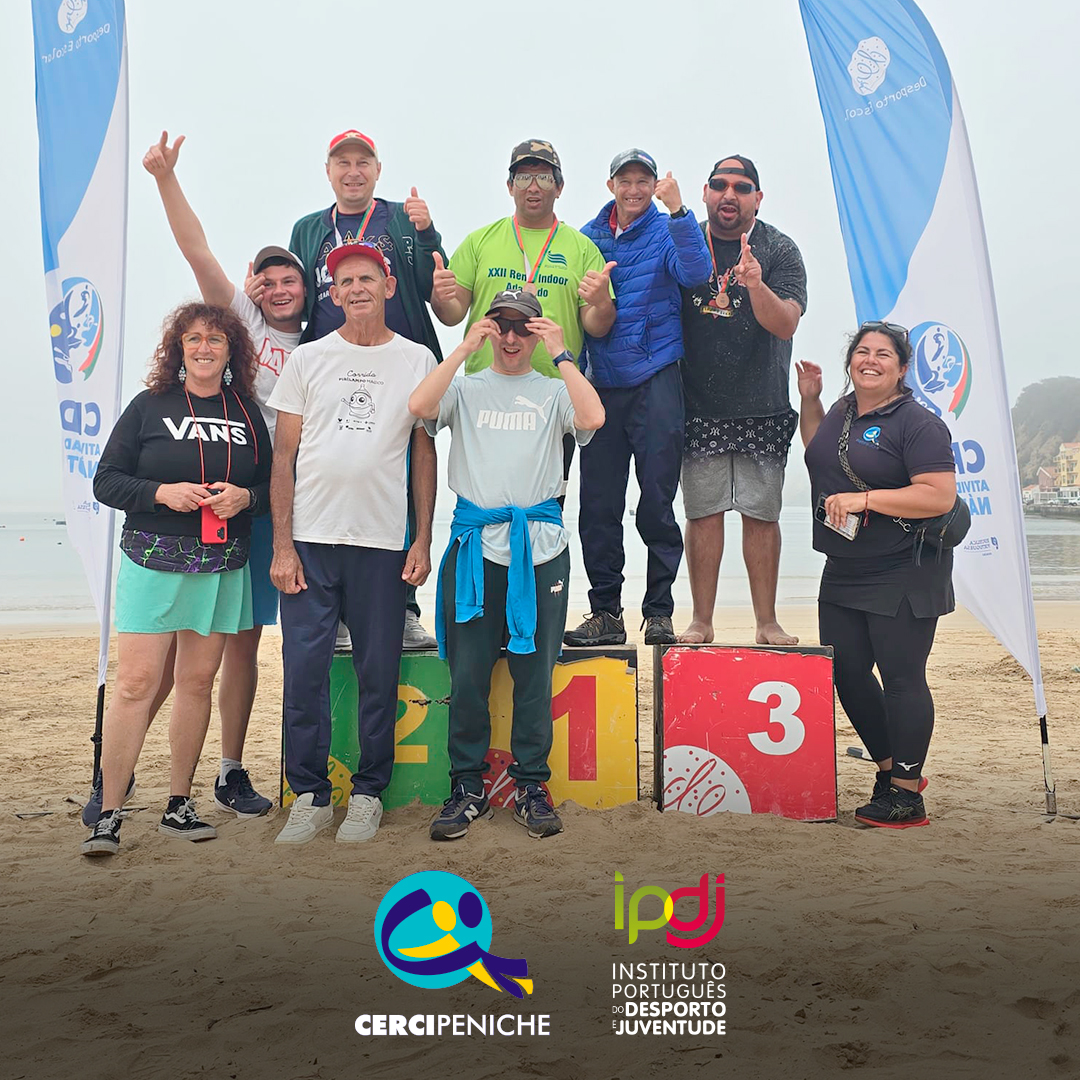 Foto na praia, com o grupo de pessoas apoiadas pela Cercipeniche e monitoras, no pódio. Logos da Cercipeniche e do IPDJ.