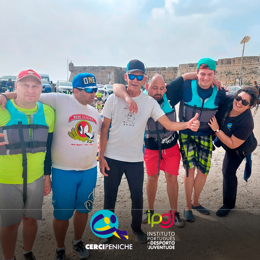 Grupo de pessoas apoiadas pela Cercipeniche, na Marina de Peniche, antes da atividade aquática. Logótipos da Cercipeniche e do IPDJ.