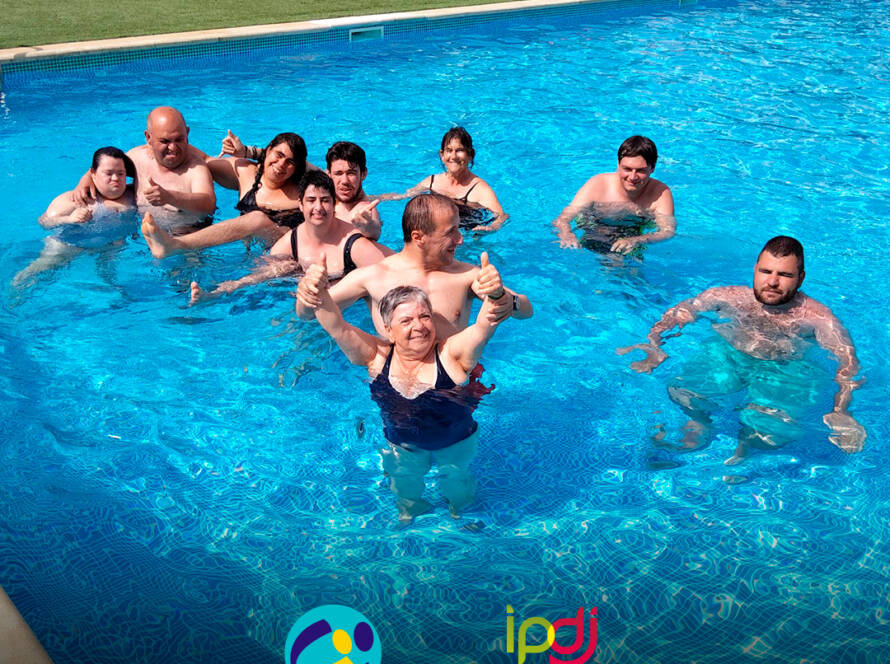 Pessoas apoiadas a sorrir para a fotografia dentro da piscina. Logo da Cercipeniche e do IPDJ.