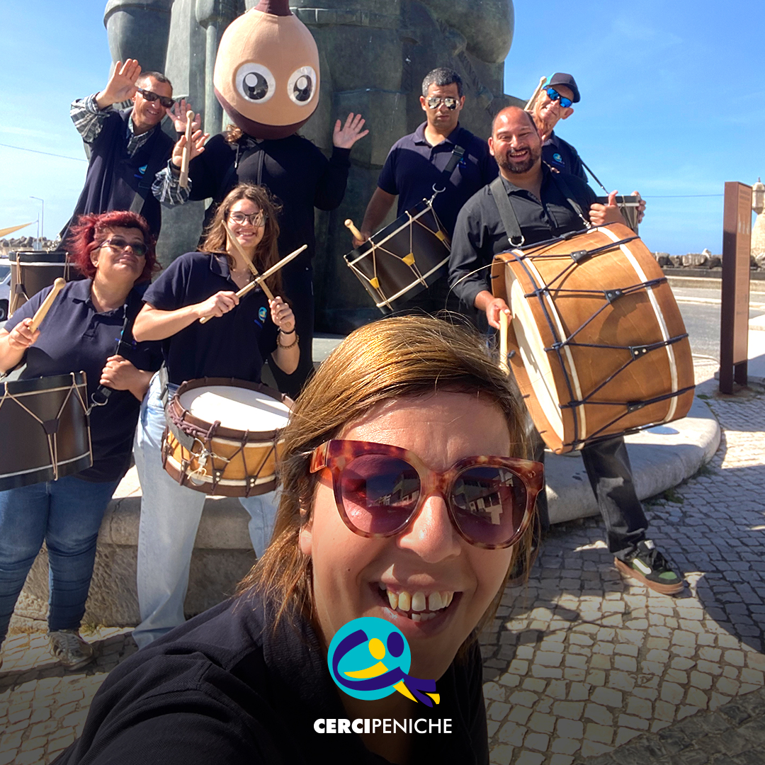 Grupo de Bombos da Cercipeniche pousam para a foto junto à estátua do Pescador, ao pé da ribeira. Logo da Cercipeniche.