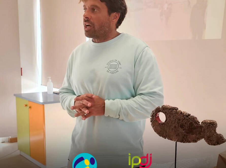Calili durante a sessão, enquanto partilha conhecimentos e recomendações sobre segurança na água e no mar. Logo da Cercipeniche e do IPDJ.