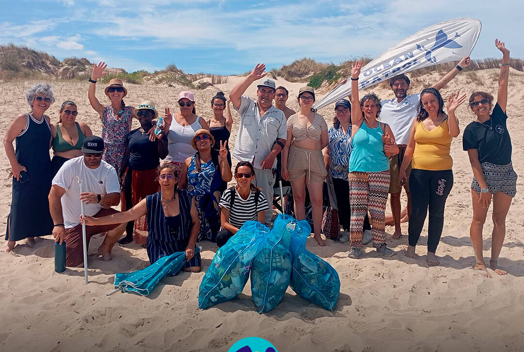 Fotografia de grupo na praia, no final da ação de sensibilização, com pessoas apoiadas pela Cercipeniche e elementos da Ocean Patrol. Logo da Cercipeniche.