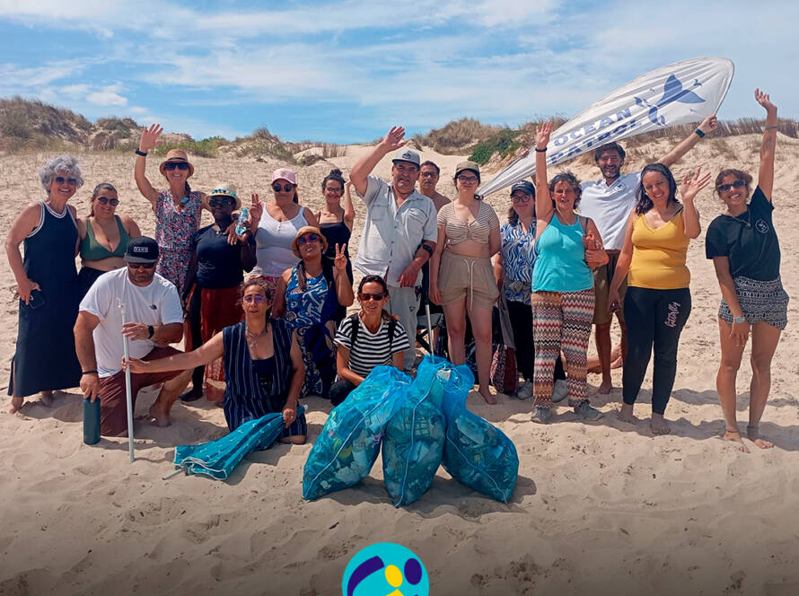 Fotografia de grupo na praia, no final da ação de sensibilização, com pessoas apoiadas pela Cercipeniche e elementos da Ocean Patrol. Logo da Cercipeniche.