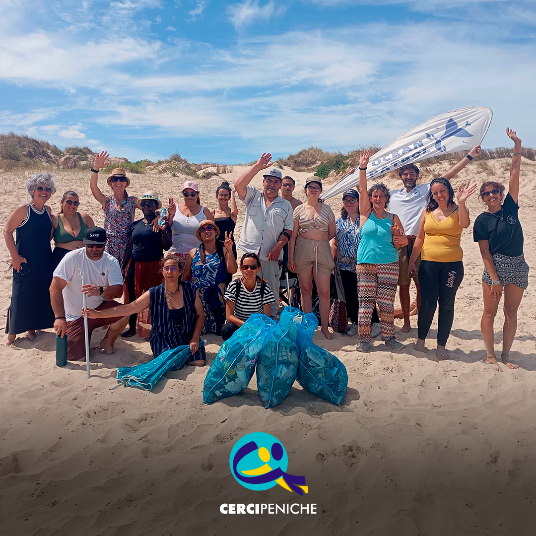 Fotografia de grupo na praia, no final da ação de sensibilização, com pessoas apoiadas pela Cercipeniche e elementos da Ocean Patrol. Logo da Cercipeniche.