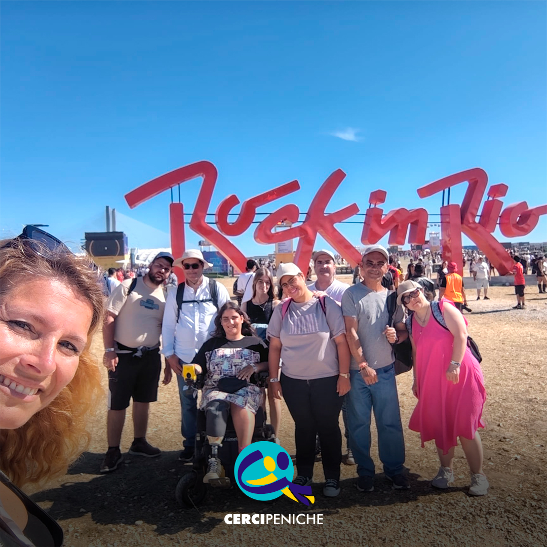 Pessoas apoiadas pela Cercipeniche pousam para a foto junto à entrada do Rock in Rio Lisboa. Ao fundo vê-se o logótipo do "Rock in Rio". Logótipo da Cercipeniche.