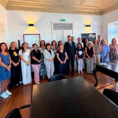 Fotografia de grupo, no interior de uma sala da Câmara Municipal de Peniche. Ao centro encontra-se o Presidente da Câmara Municipal de Peniche, rodeado pelos representantes das organizações que integram o protocolo de colaboração para as refeições escolares. O grupo está de pé e olha para a câmara. Logótipo da Cercipeniche.