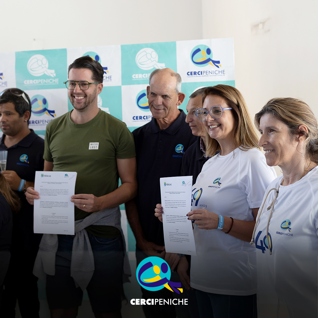 Grupo de seis pessoas posa para a fotografia em frente a um painel com os logótipos da Cercipeniche. Um homem de t-shirt verde e uma mulher com a t-shirt comemorativa dos 49 anos seguram documentos, enquanto os restantes participantes sorriem. Na parte inferior da imagem encontra-se o logótipo da Cercipeniche.