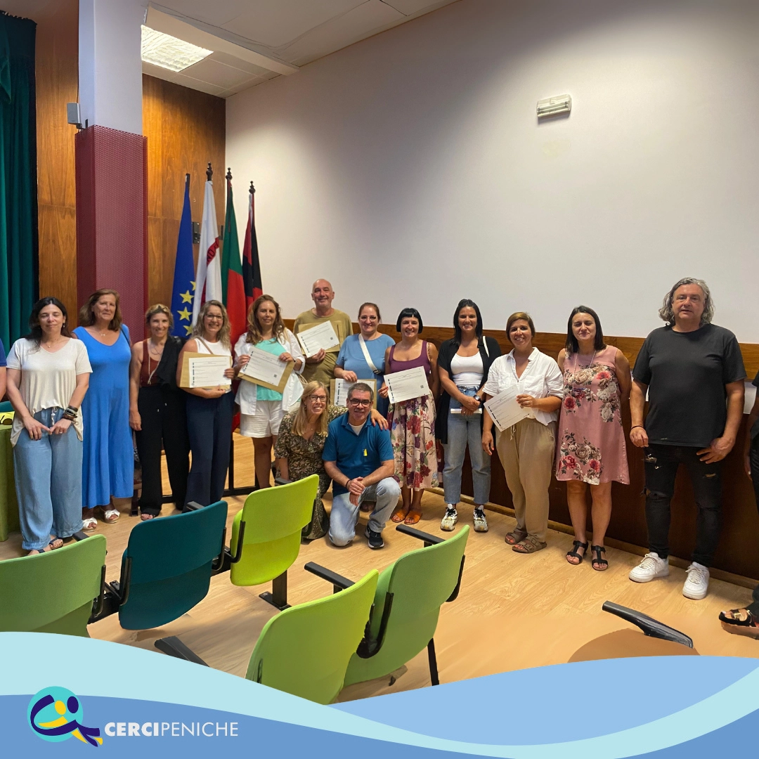 Grupo de pessoas colaboradoras da Cercipeniche, junto a formadores em cerimonia de entrega de certificados RVCC. Logotipos e elemento gráfico.